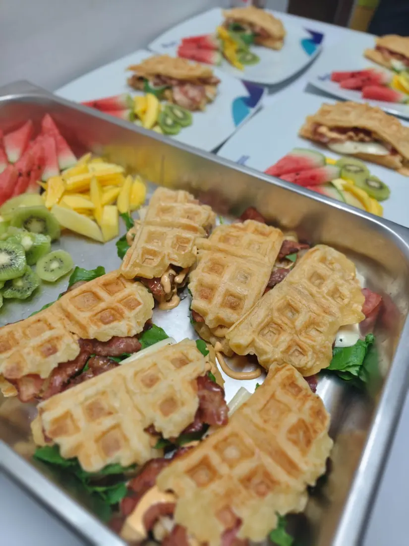 Desayuno empresarial de waffles con tocineta y fruta fresca